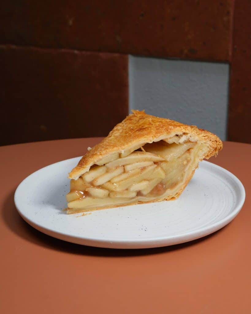 Apple Pie slice showing layered apple filling and golden crust at Dulce de Saigon