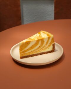 Pumpkin Cheesecake slice with pumpkin swirl and graham cracker crust at Dulce de Saigon